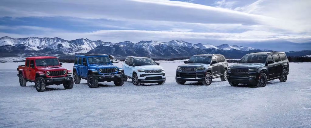 A lineup of five Jeep vehicles parked on a snowy landscape.