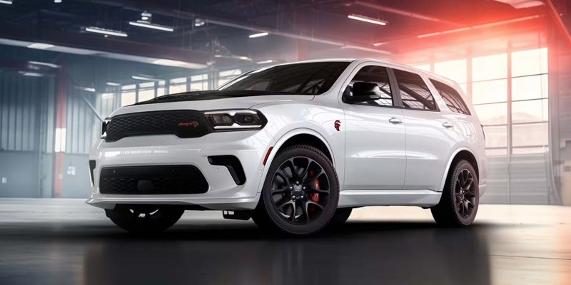 White Dodge Durango SRT Hellcat with black wheels and red brake calipers parked inside a garage.